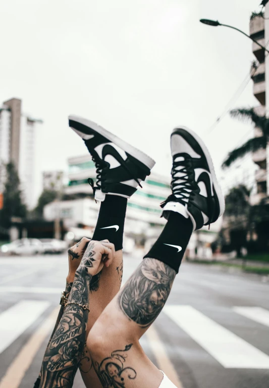 a tattooed arm and leg holding up a shoe