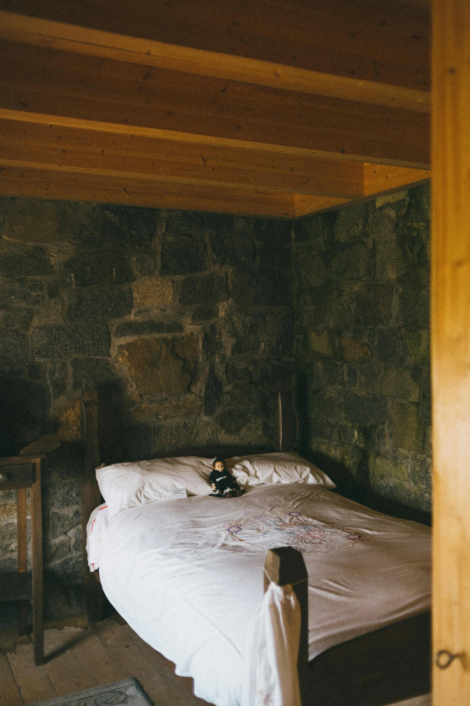 a person's legs in front of a bed with stone walls