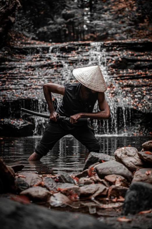 the man in the white hat is standing in some water and holding a cane