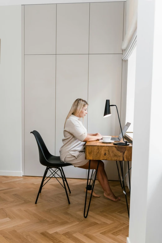 a woman is sitting at a desk with her laptop