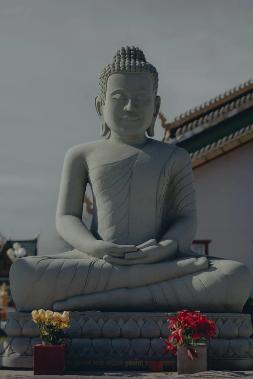 a buddha statue and flowers on a stone pedestal