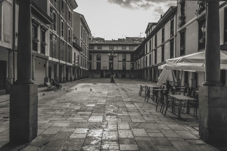 an empty courtyard with tables and umbrellas on the ground