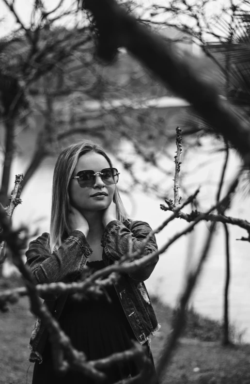 a beautiful young lady holding onto nches in a black and white po