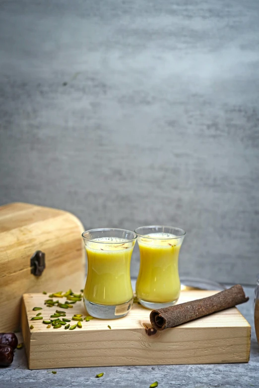 two glasses of orange juice sitting on a table with cinnamon sticks