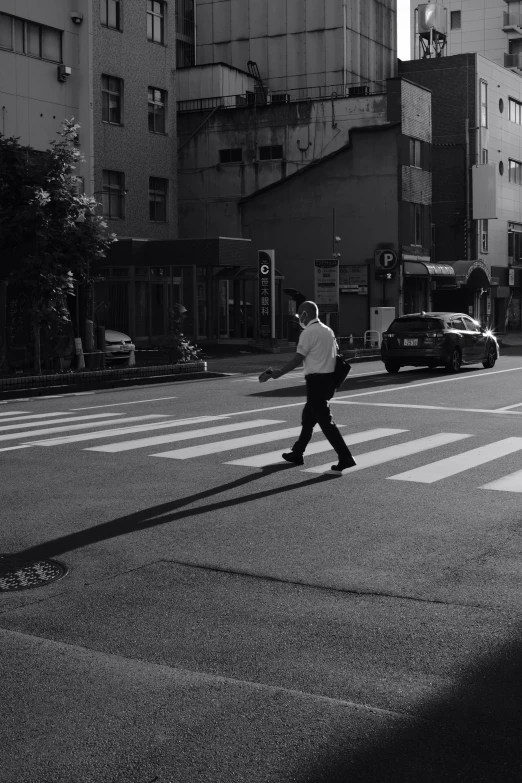 black and white po of man walking across the street