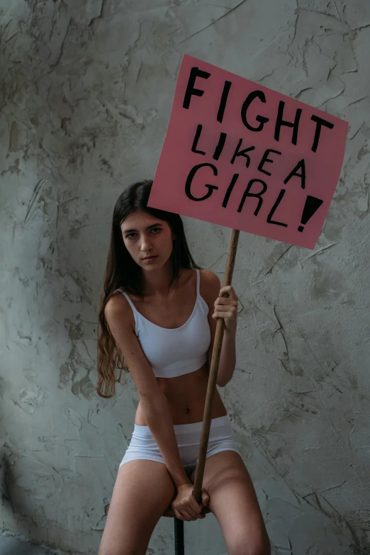 a girl in a tight underwear holds up a sign