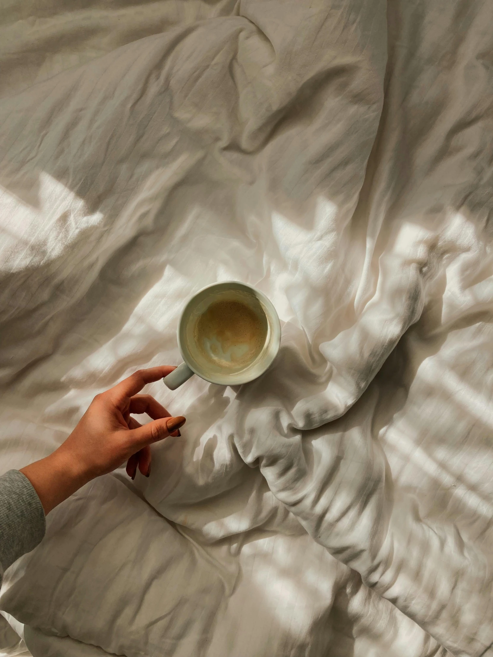 a woman is holding a spoon that is in a bowl on a bed