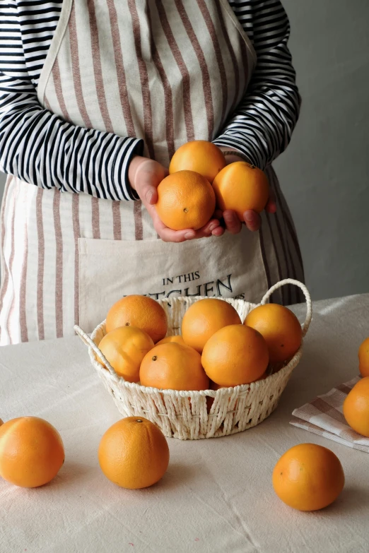 a person holding up oranges in a basket