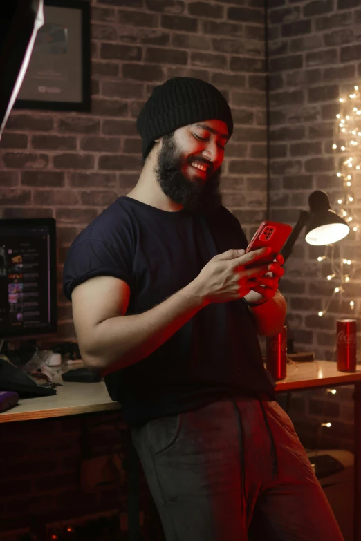 a man in a black hat is holding a red cell phone