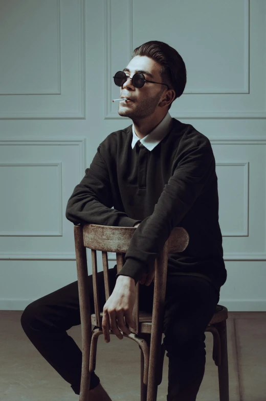 a man sitting on top of a wooden chair with sunglasses