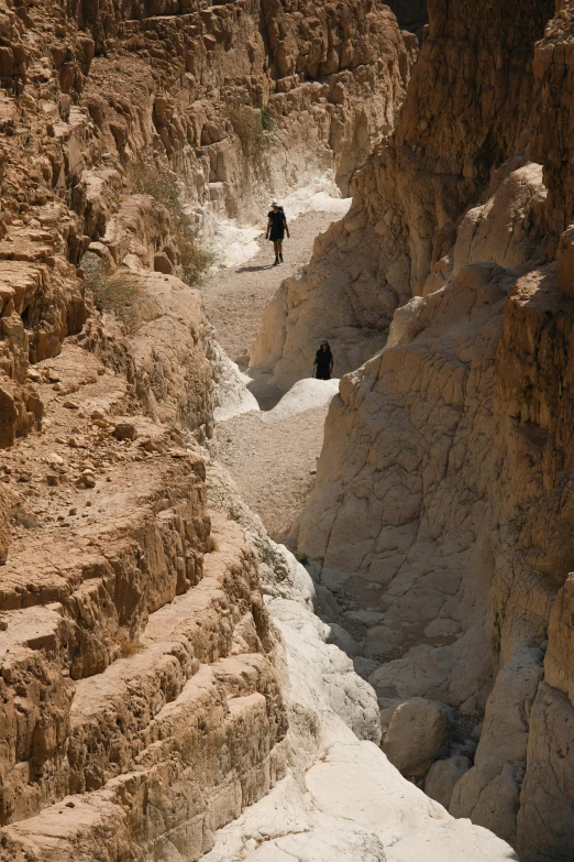 people are walking in a canyon surrounded by rocky walls