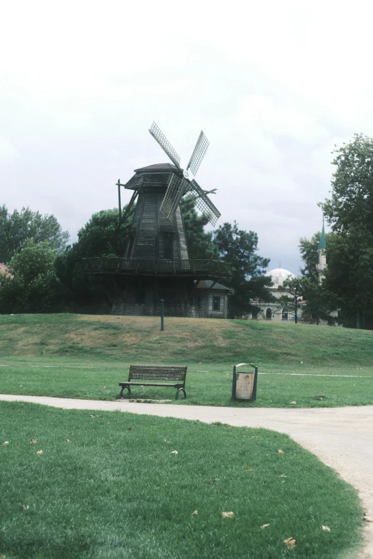 a windmill sitting on top of a hill near a park