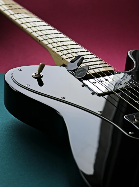 a black guitar with gold strings against a colorful background