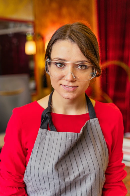 a woman wearing glasses and an apron with black stripe on it
