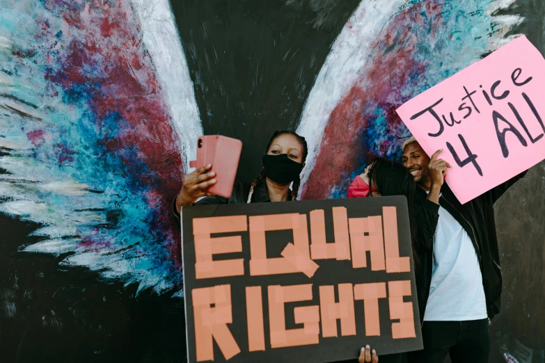 two people hold signs while holding pink and blue wings