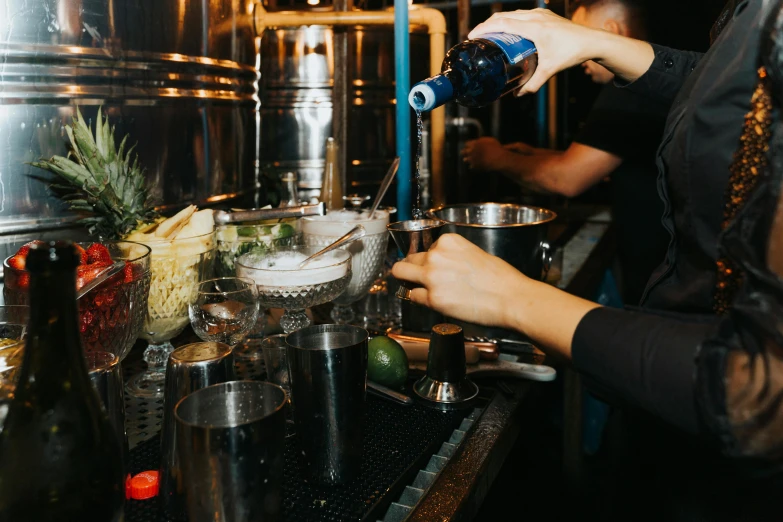 people are preparing food in the kitchen next to stainless steel pots