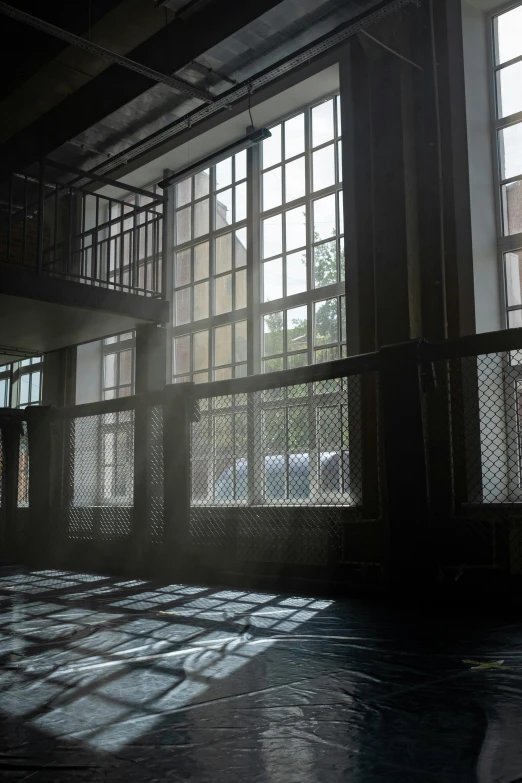 the sun streams through three windows in an empty building