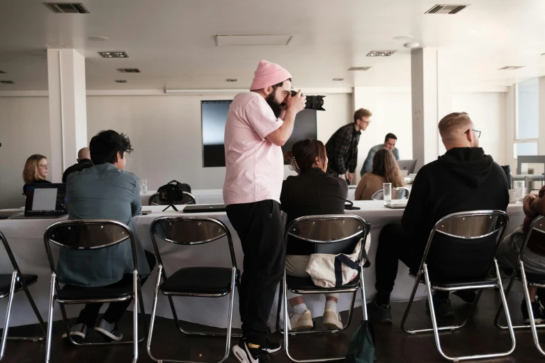 people in an office setting with chairs and desks with one person taking a po