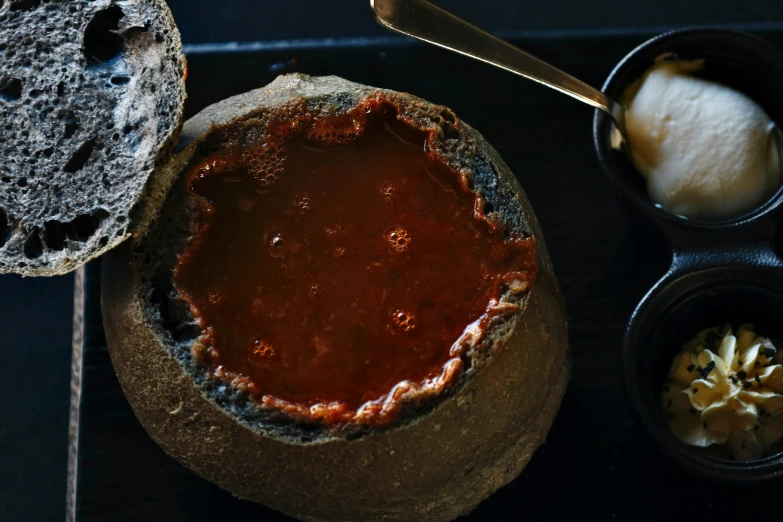 a piece of bread sits next to a bowl of tomato sauce