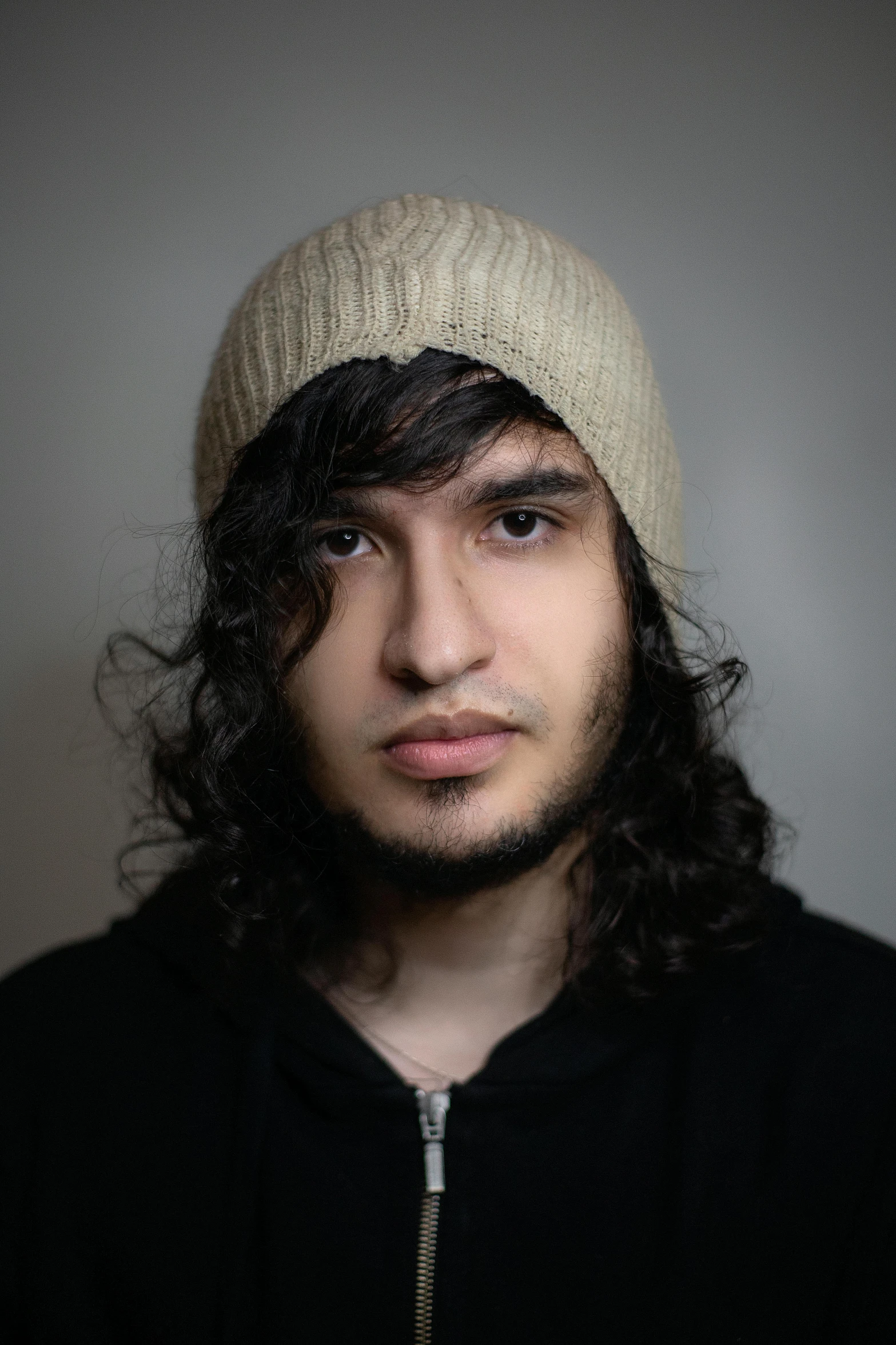 a young man wearing a winter hat and a black jacket