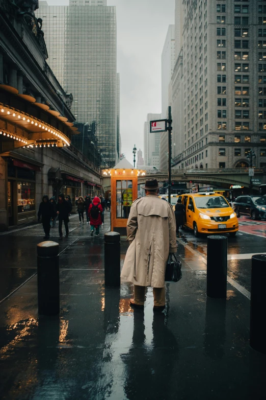 man walking in the rain down a city street