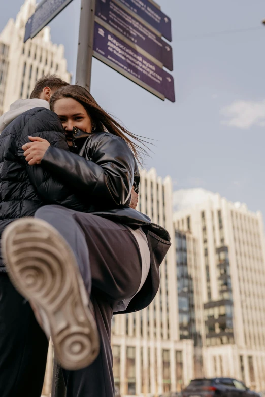 two people hug each other as they stand under a street sign