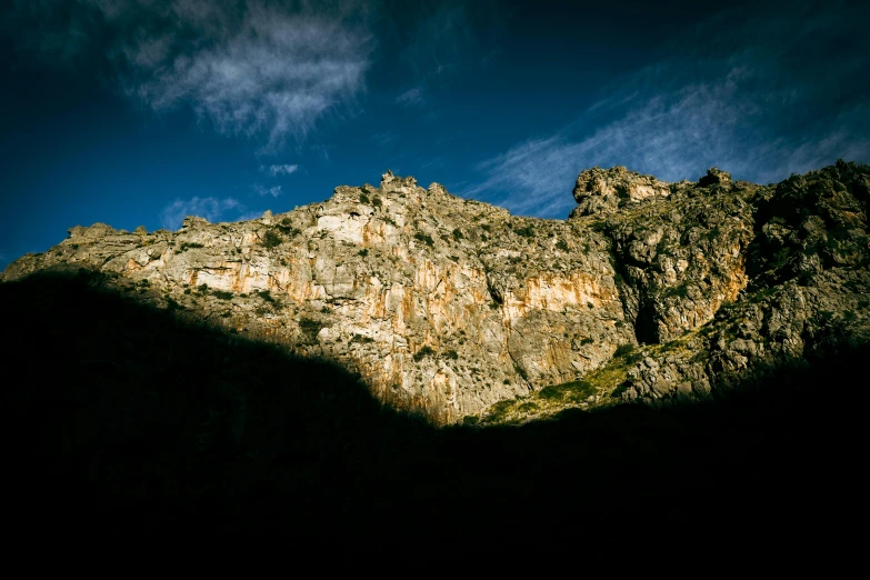 a mountain cliff with mountains in the background