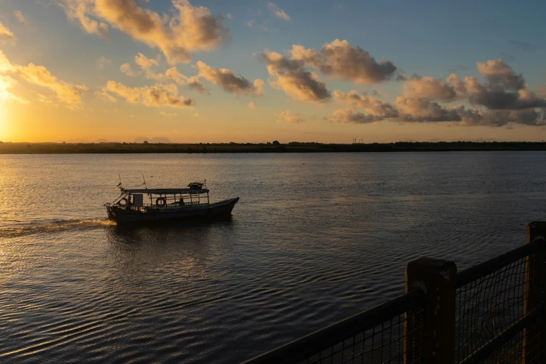 a boat traveling down the river at sunset