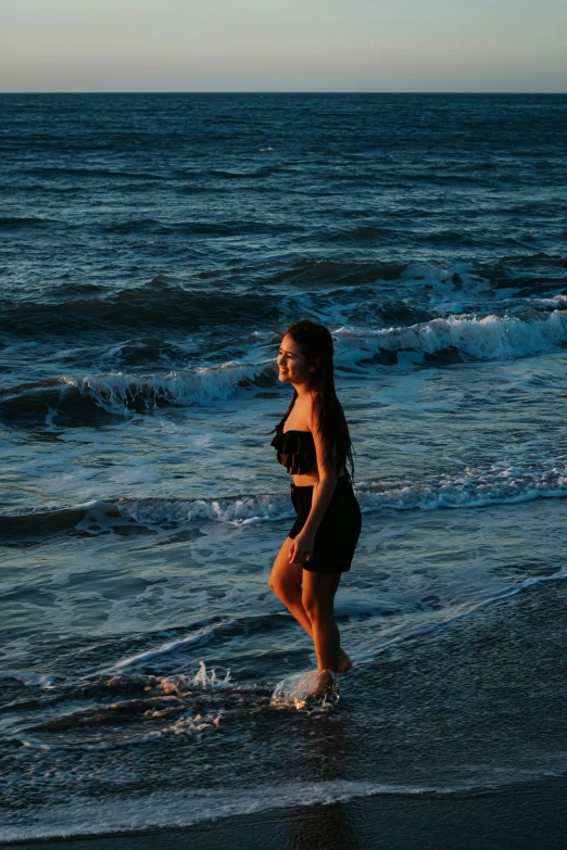 the girl is standing in shallow water at the beach