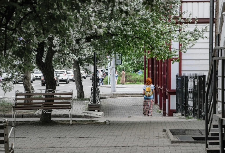 a woman standing on the side of a road next to some benches