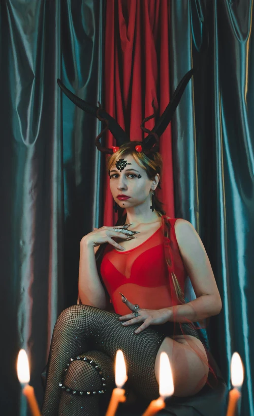 a woman sitting on the floor dressed in black tights and some candles