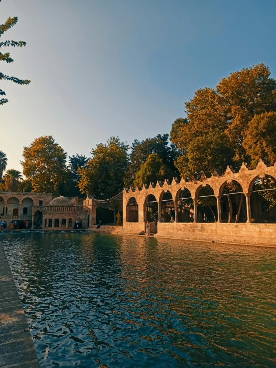 a lake and an old structure with arches and pillars