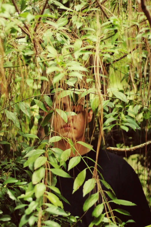 a woman peeking through the nches of a tree