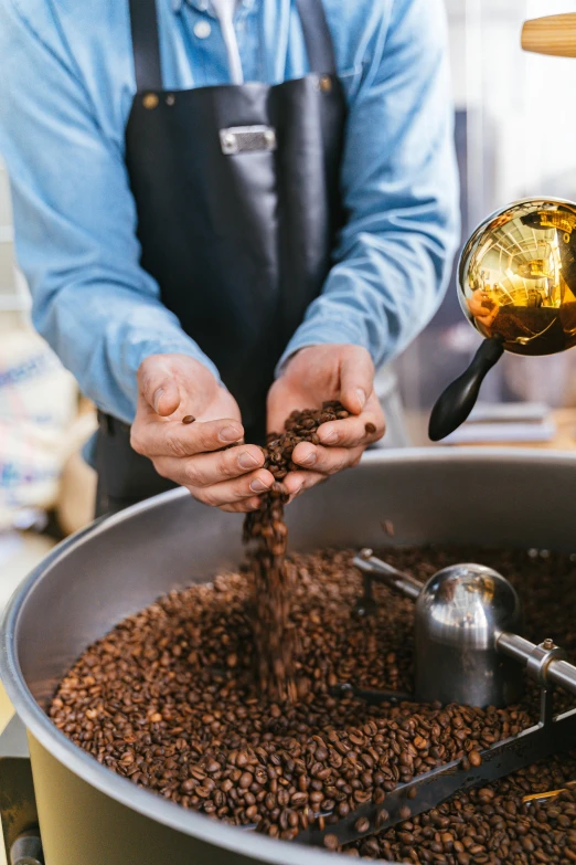 someone pouring soing into a pot that is filled with coffee beans