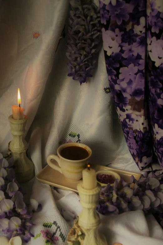 a table set with a candle, tea and flower petals