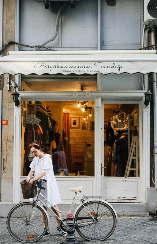 a woman on a bike with a basket in front of a store