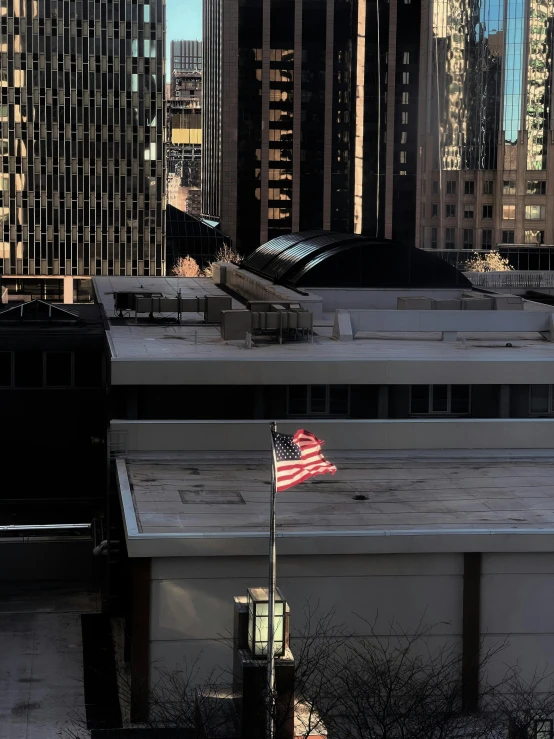 the american flag is flying on top of a building in a city