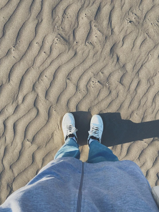 a person stands on the sand with their shoes on