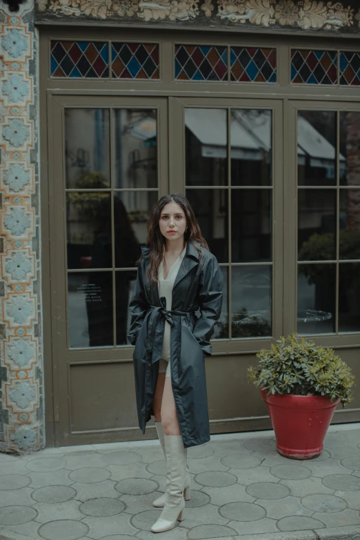 a woman standing outside of a building, wearing boots