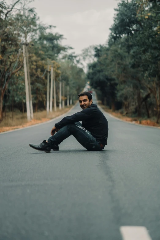 a man sitting on the road wearing black