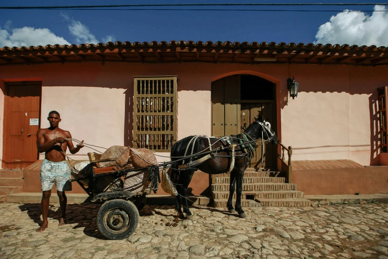 a man and a horse pulling a cart down the street