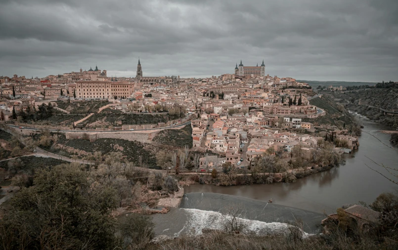 view of city surrounded by water and hills under dark clouds