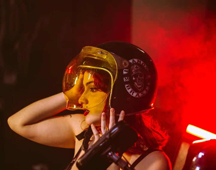 a woman with yellow paint on her face holding a beer in front of red lights