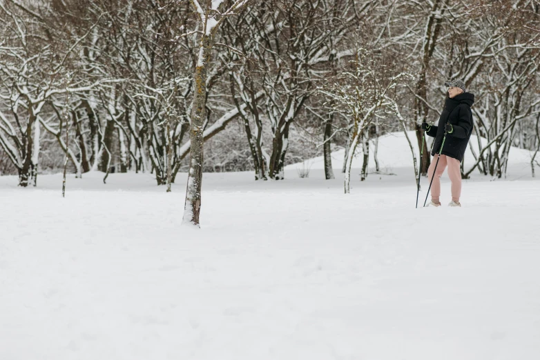 woman in black jacket walking down snow covered field