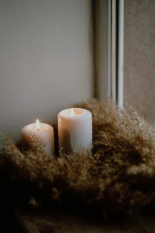 a few white candles sitting on a windowsill