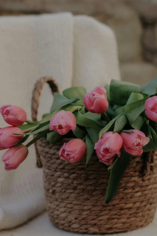 a basket of pink tulips sitting on a chair