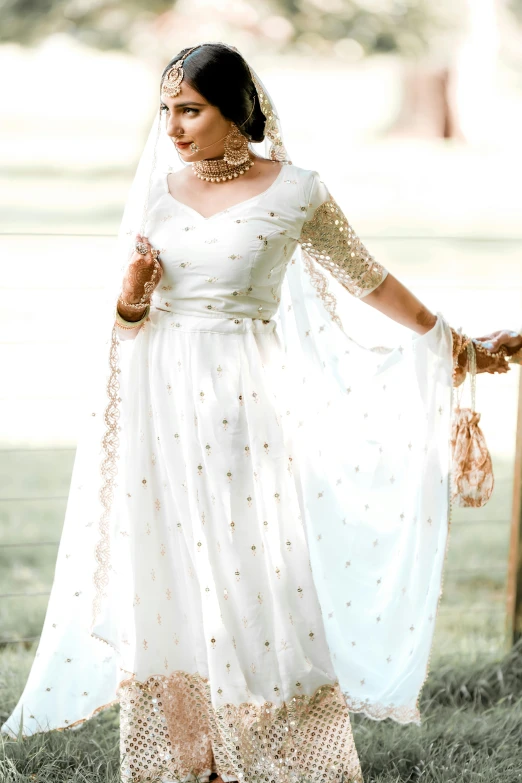 a woman in a dress standing next to a gate