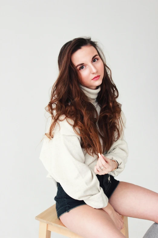 a girl sitting on a chair wearing a white shirt and black skirt