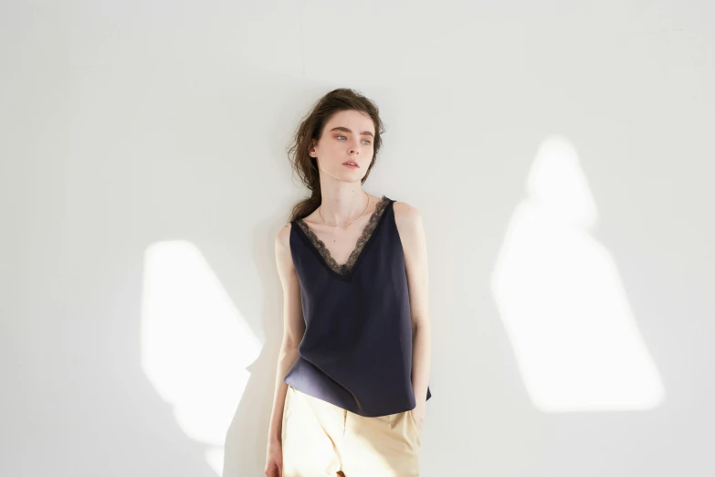 a woman standing next to a wall wearing a black shirt and cream shorts