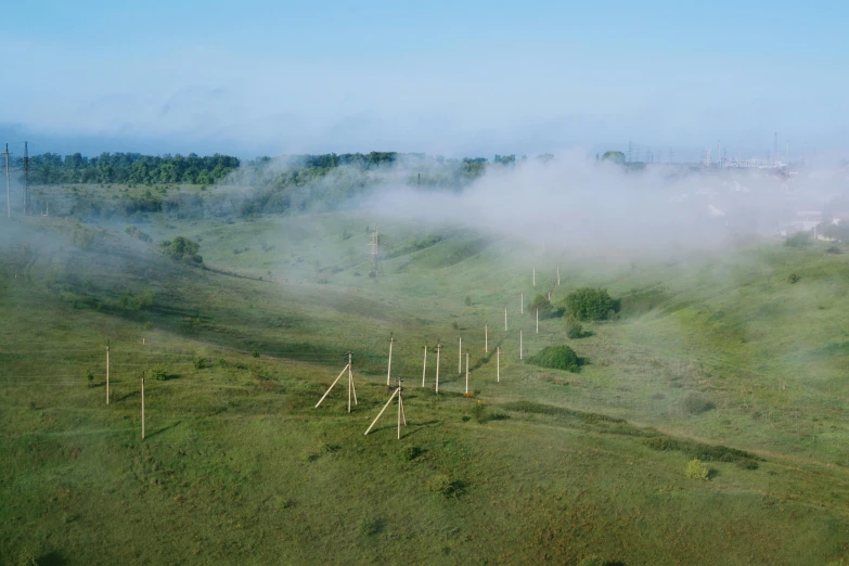 a very foggy landscape with trees on the hill